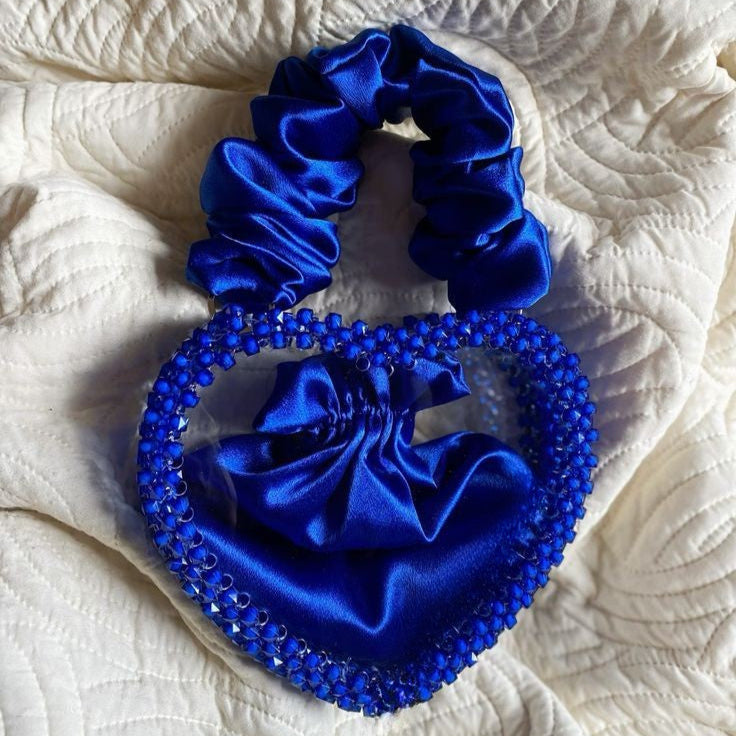 Blue scrunchie with decorative elements on a textured white surface